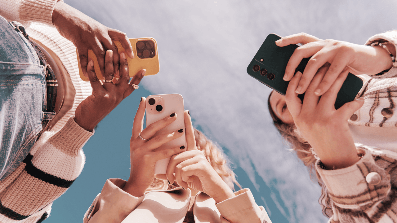 Jóvenes de la Generación Z interactúan con sus smartphones, dispositivos clave para el acceso a la inteligencia artificial, en un contexto de creciente uso y preocupación por sus efectos.